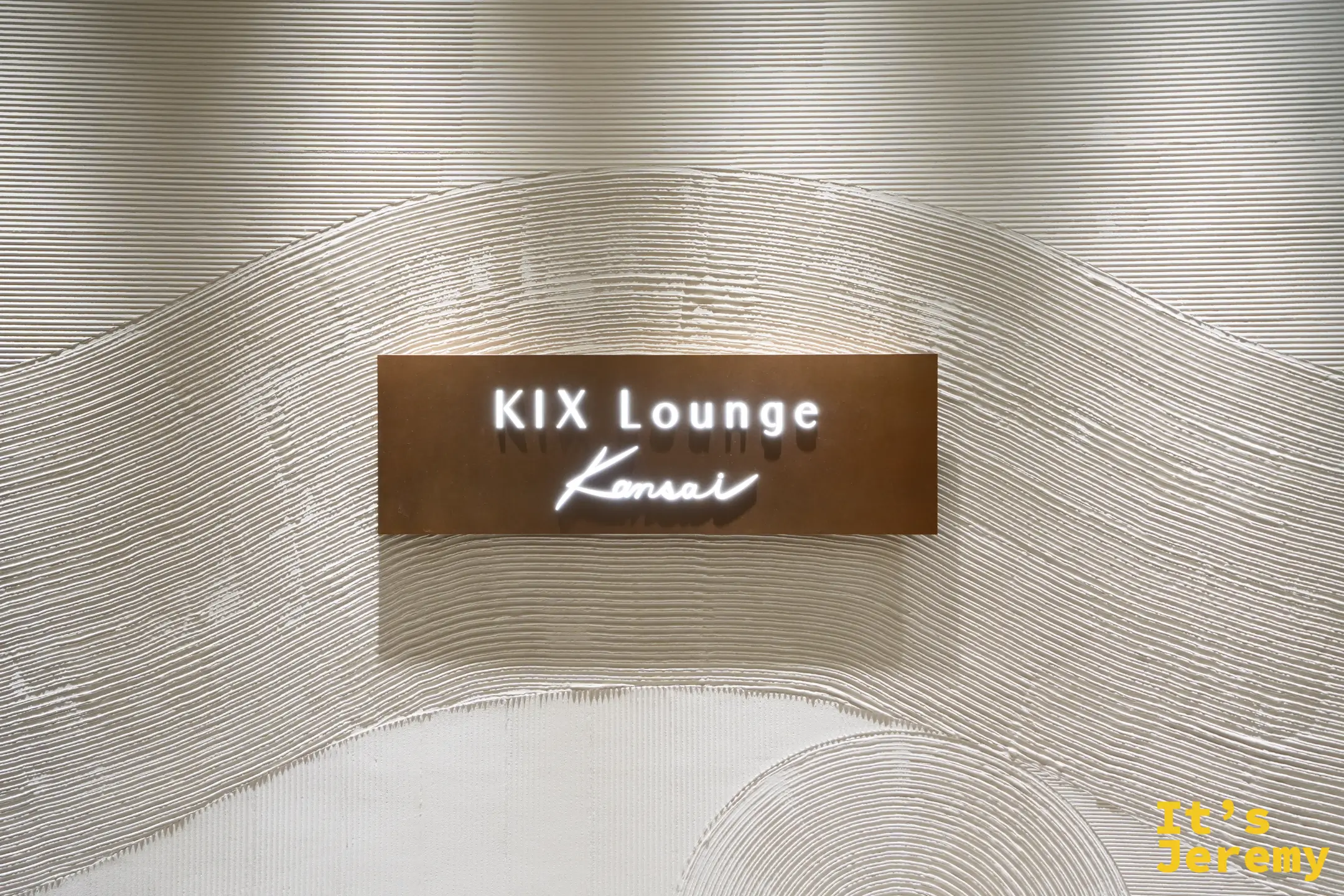 KIX Lounge Kansai 入口招牌，背景是水波紋造型的白色牆面