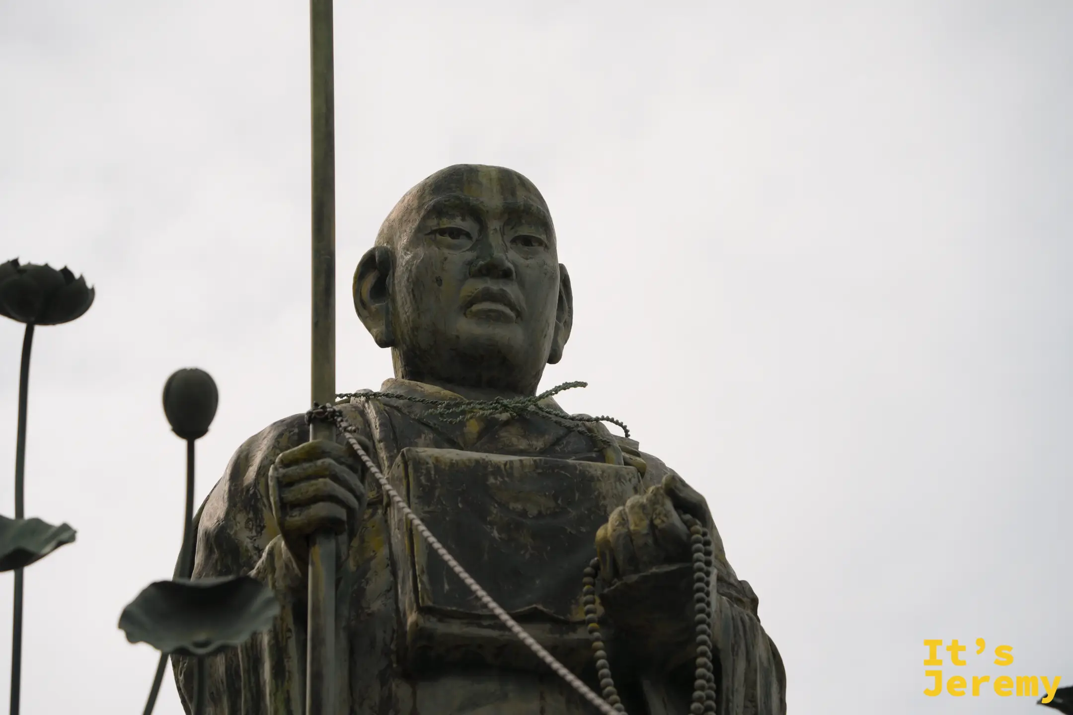 弘法大師修行像，手持錫杖與念珠，身旁有銅製蓮花