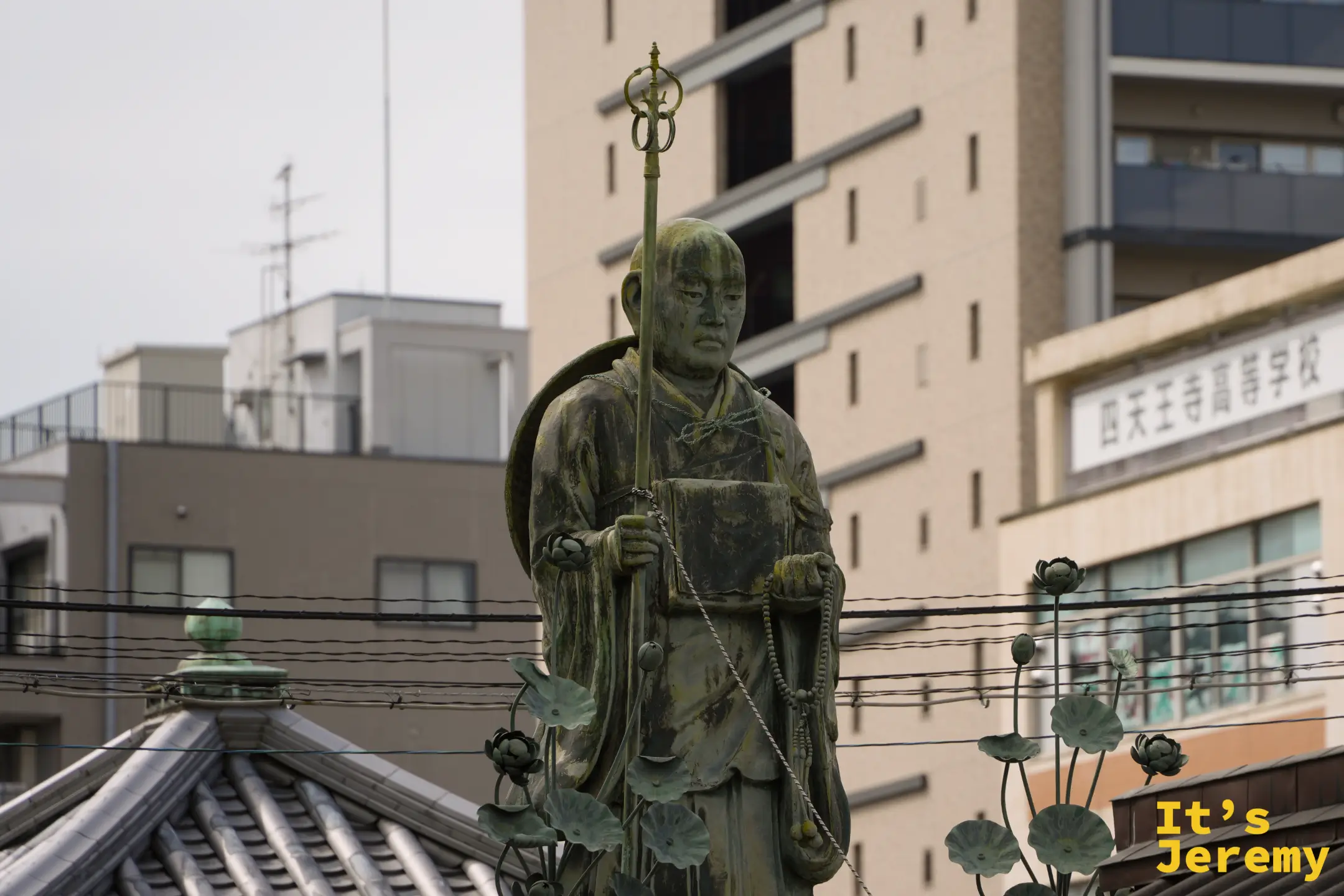 弘法大師修行像與後方四天王寺高等學校的招牌