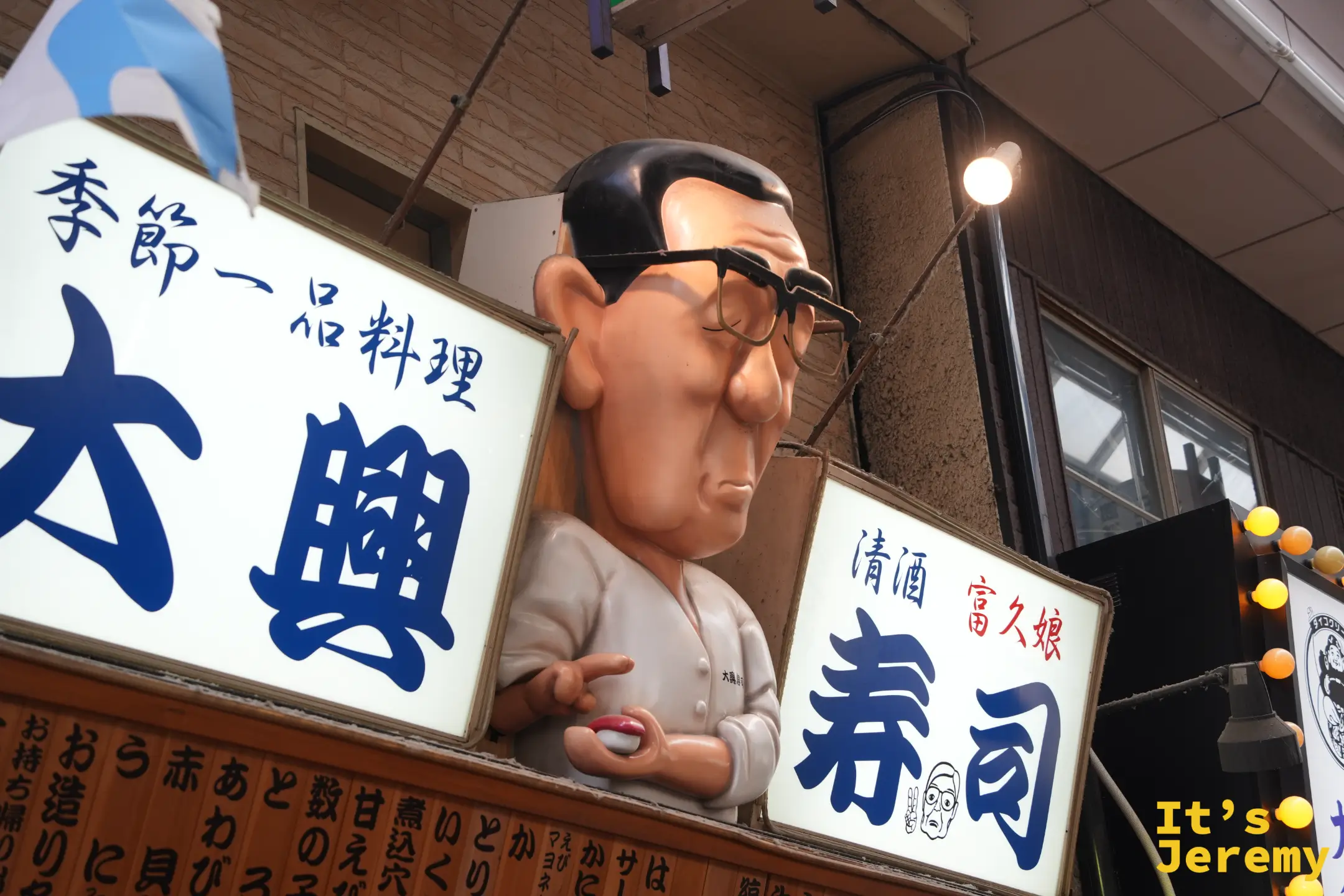 壽司店招牌中間戴眼鏡的大叔人偶