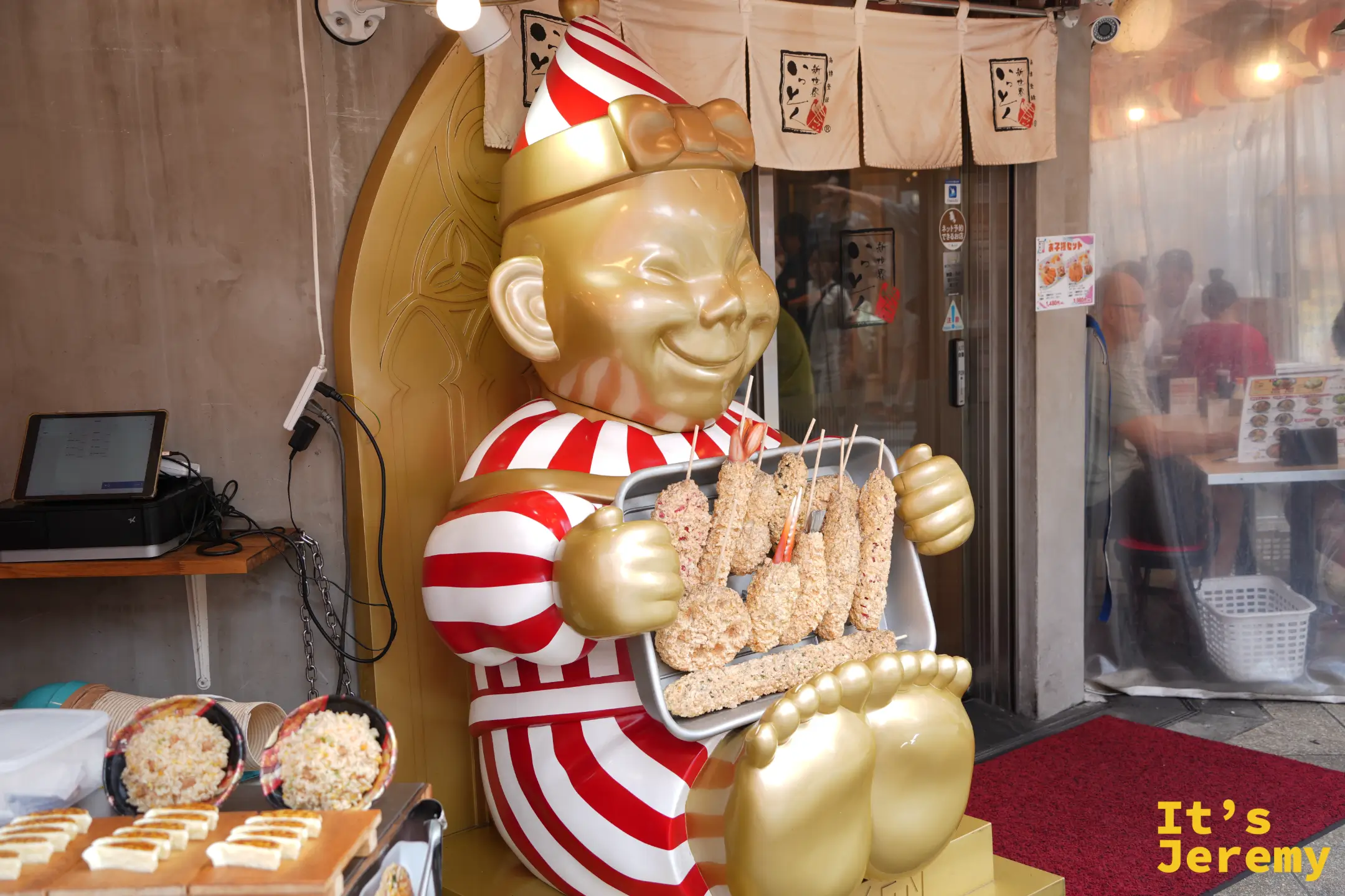 串炸店門口穿紅白條紋衣、捧著串炸盤的比利肯