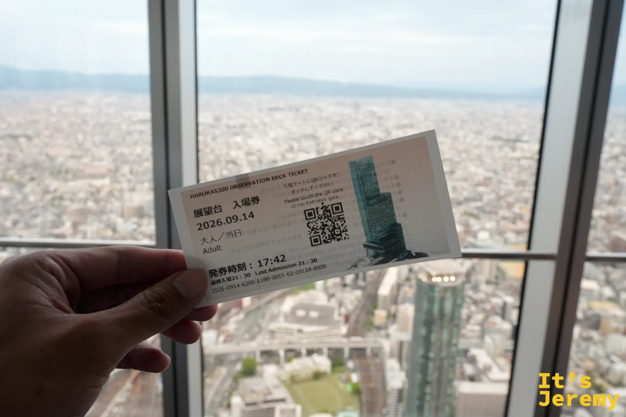 手持 HARUKAS 300 展望台入場券，背景是玻璃窗外的大阪街景